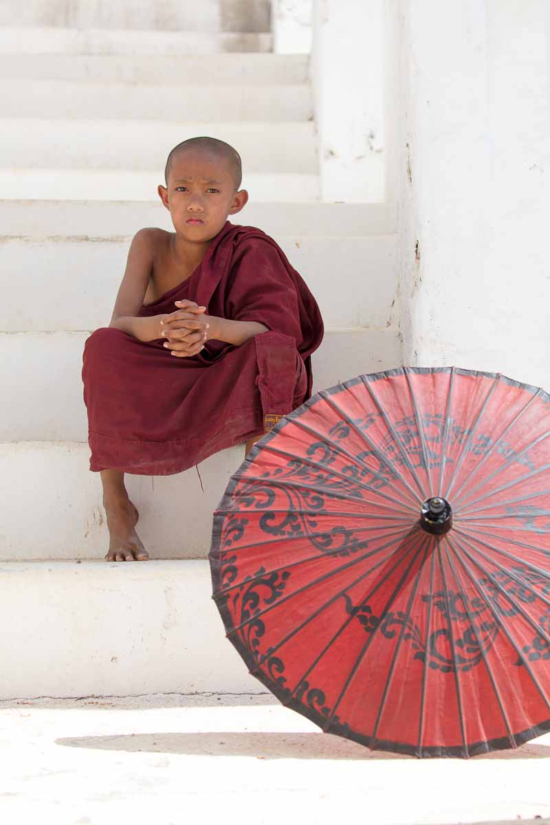 A young monk sits on the steps at Hsinbyume Pagoda in Mingun, Myanmar