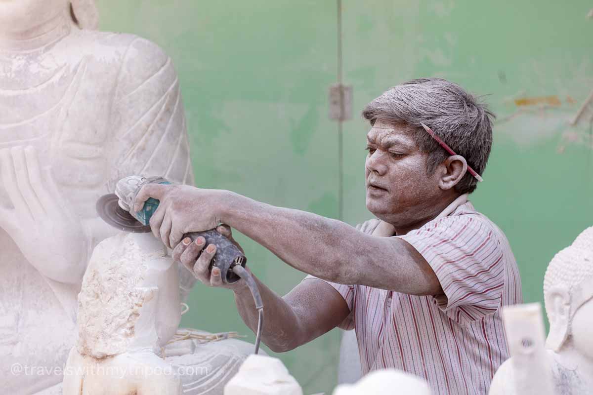 A man carving marble statues with an angle grinder